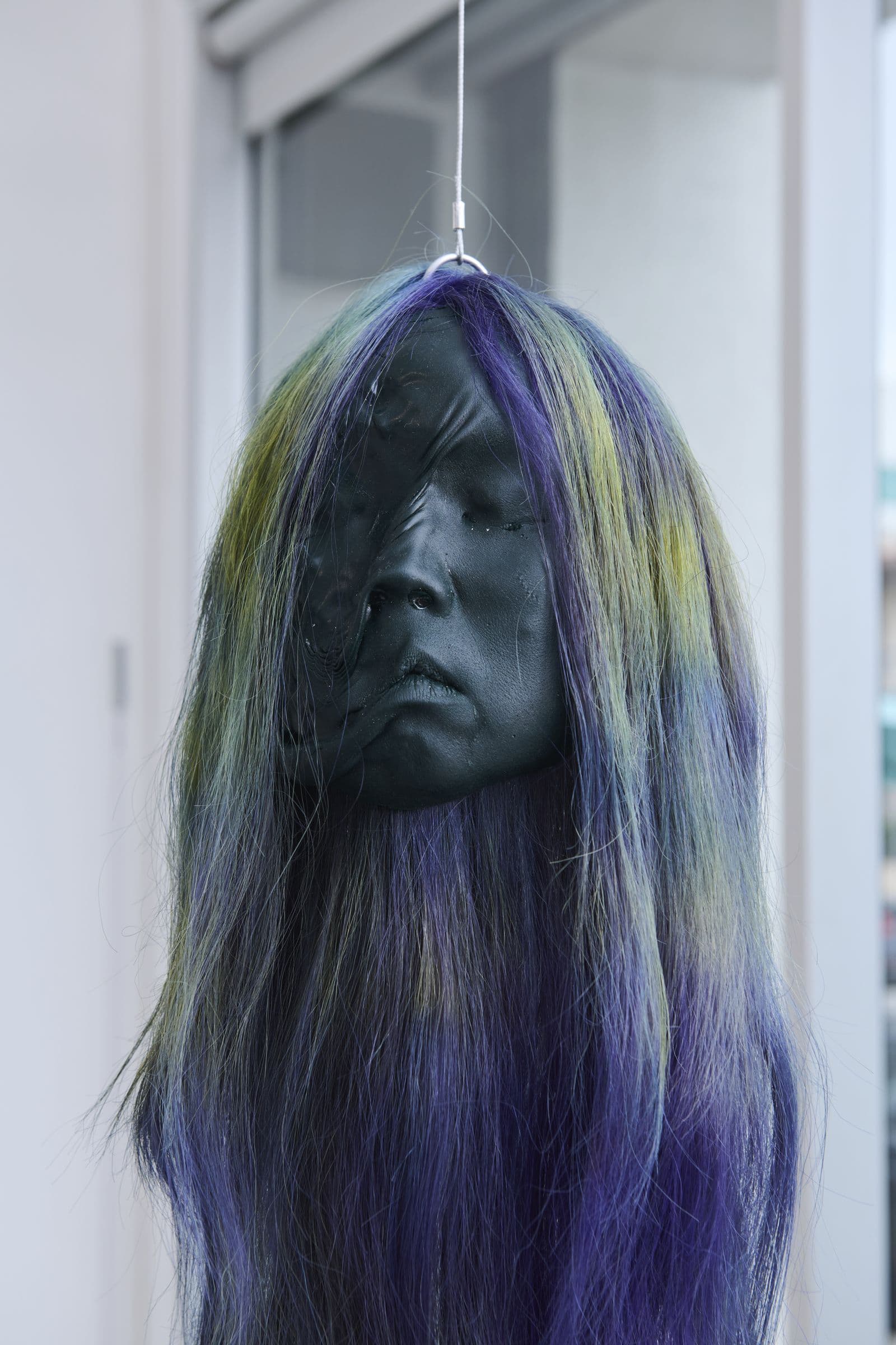Detail of a dark cast face with multicolored hair, part of an installation at Lola Gallery